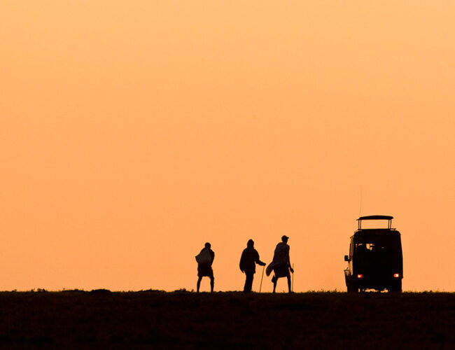 Silhouettes of a crew and vehicle at sunset